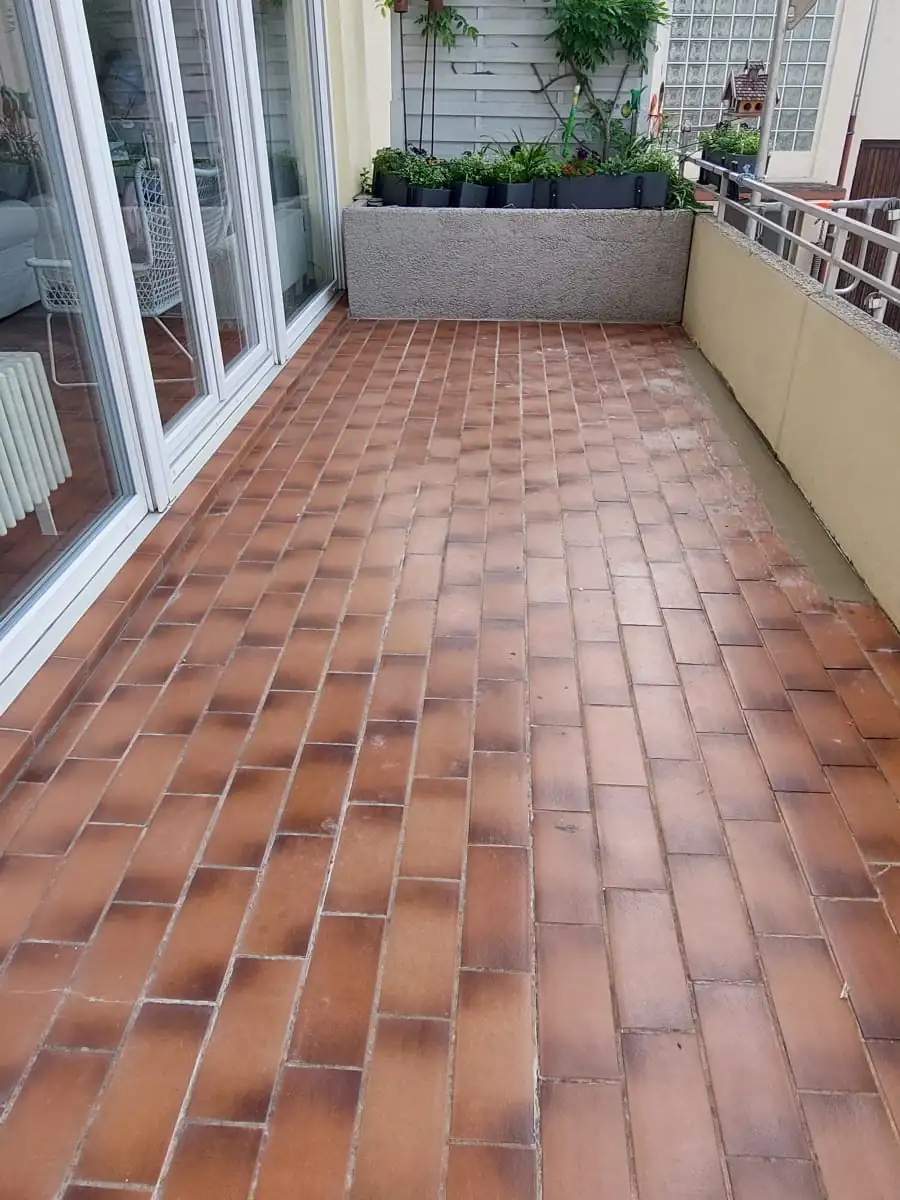 Vorher: Terracotta-Fliesen auf langem Balkon – ersetzt durch hellgrauen Steinteppich