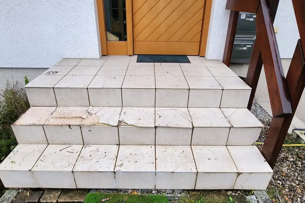 Vorher: Abgeplatzte Natursteinplatten an der Haustür – fugenlos in Beige